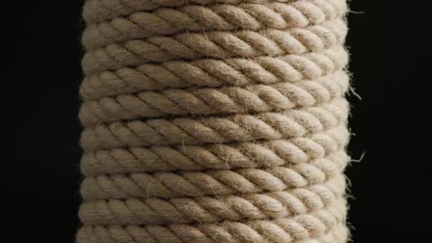Vertical coil of flax rope slowly rotating on black background — Vídeo de stock