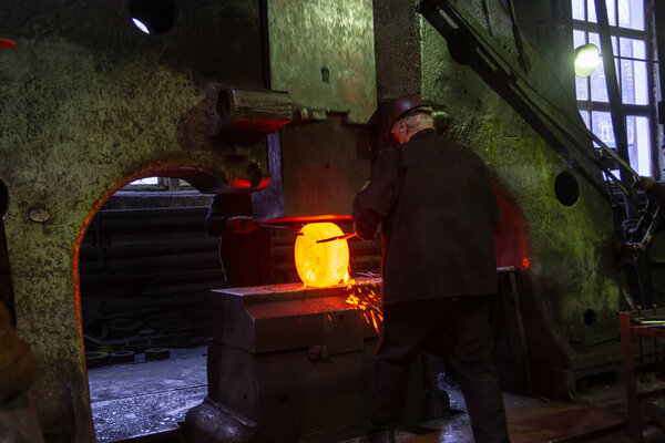 кузнец, ковавший большой кусок горячей стали на старом заводе