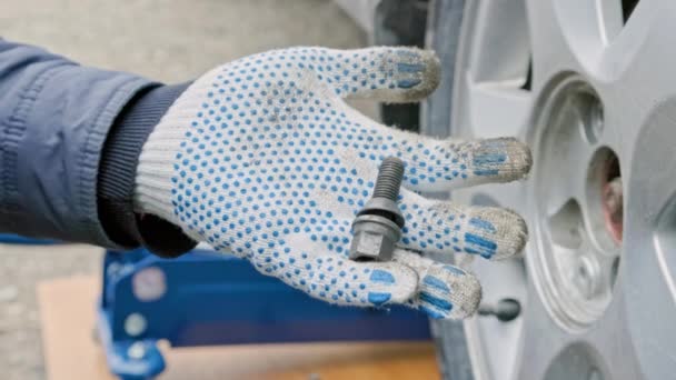Hand in glove holding car wheel bolt — Stockvideo