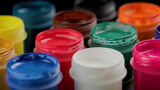 Loopable rotating close-up background of opened small gouache paint jars — Stock video