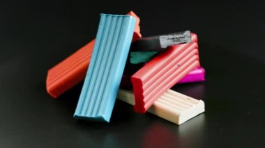 small pile of rectangular pieces of colored plasticine rotating on black