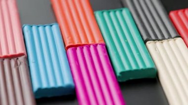 rectangular pieces of colored plasticine rotating slowly on black flat surface