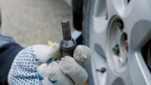 Mechanic hand in fabric glove holding car wheel bolt — Stock Video
