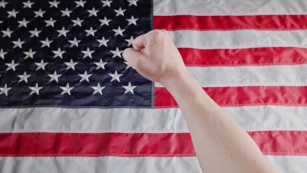 Rised caucasian fist on blurry US flag background — Stock video
