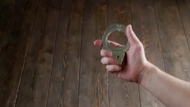 bare caucasian hand holding silver steel handcuffs on wooden board background