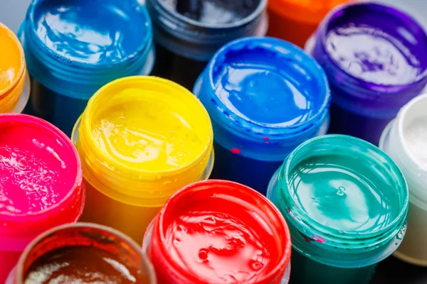 full-frame close-up background of opened small gouache paint jars