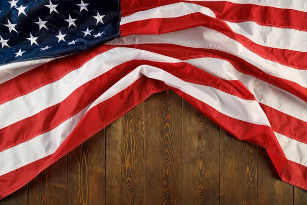 Bandera de EE.UU. arrugada sobre fondo plano de superficie de madera texturizada — Foto de Stock