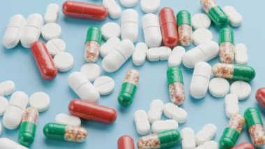 different types of medical pills and capsules rotating on blue surface