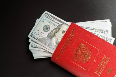 russian international passport with inserted US dollars on black background