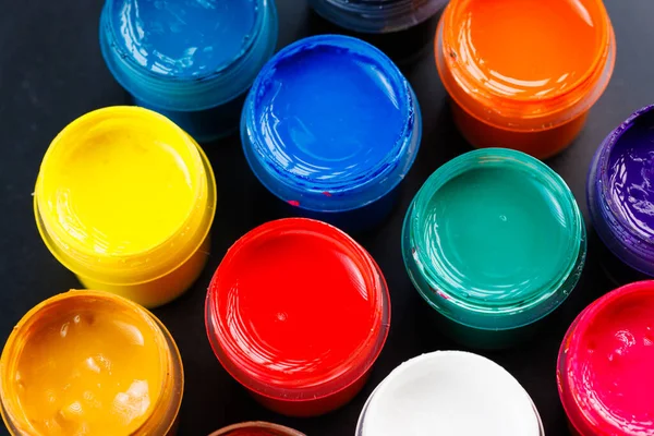 full-frame close-up background of opened small gouache paint jars