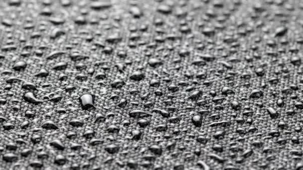 Spinning closeup background of black hydrophobic fabric covered with water drops — Vídeo de Stock