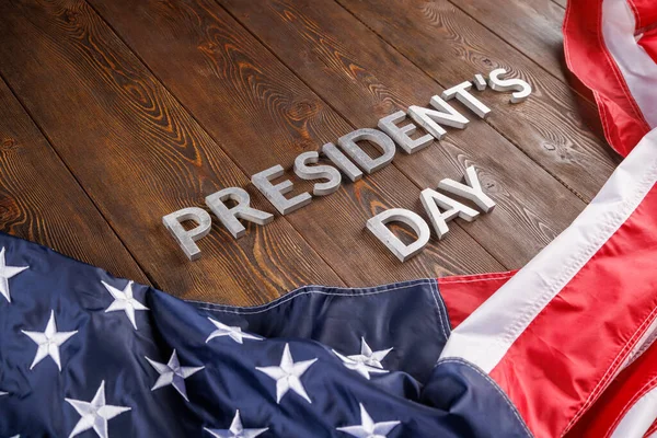 Words presitdents day laid with silver letters on wooden surface near US flag — Stockfoto