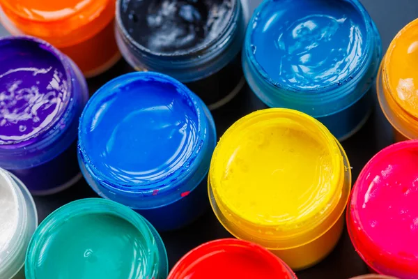 full-frame close-up background of opened small gouache paint jars