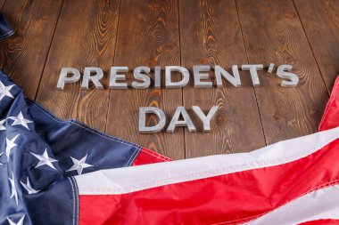 words presitdents day laid with silver letters on wooden surface near US flag