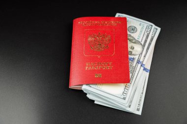 russian international passport with inserted US dollars on black background