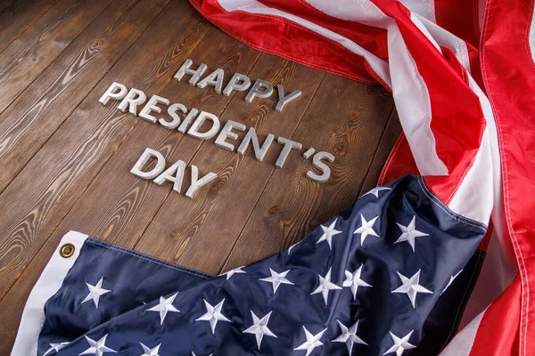 words happy presitdents day laid with real letters on wooden board near US flag