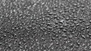 spinning closeup background of black hydrophobic fabric covered with water drops