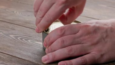 caucasian hands opens tin can with pull ring on wooden surface