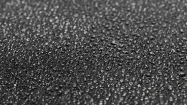 spinning closeup background of black hydrophobic fabric covered with water drops