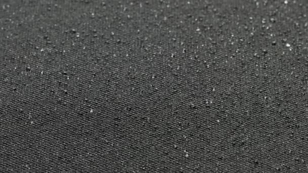 Spinning closeup background of black hydrophobic fabric covered with water drops — Vídeo de stock