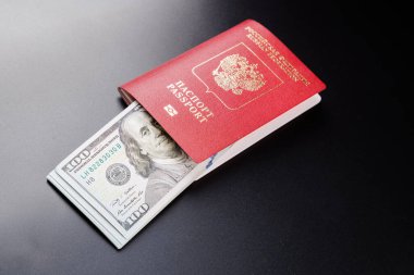 russian international passport with inserted US dollars on black background