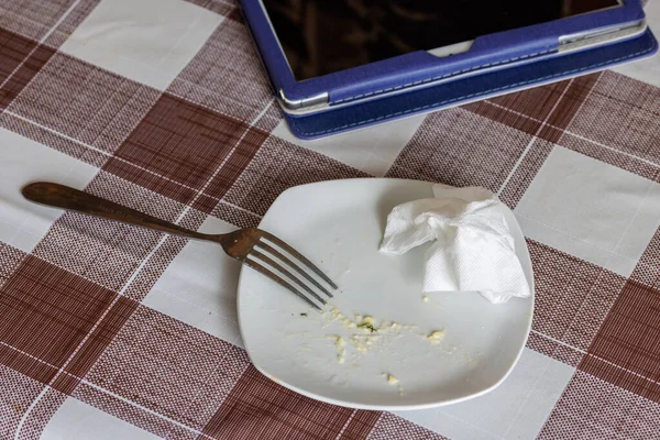 Άδειο λευκό πιάτο με υπολείμματα φαγώσιμων τροφίμων, τσαλακωμένο τραπέζι-χαρτοπετσέτα και χαλύβδινο πιρούνι — Φωτογραφία Αρχείου