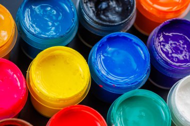 full-frame close-up background of opened small gouache paint jars