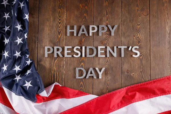 words happy presitdents day laid with real letters on wooden board near US flag