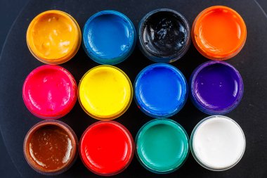 full-frame close-up background of opened small gouache paint jars