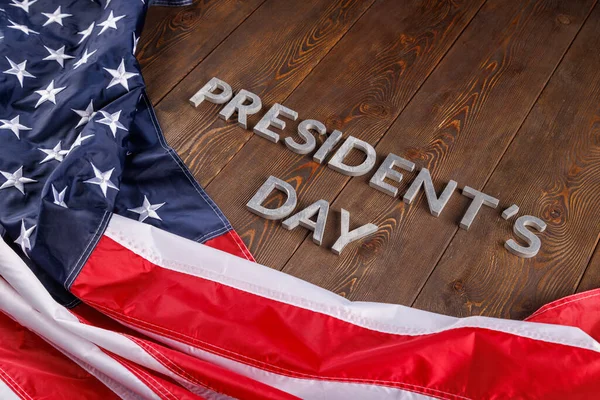 Words presitdents day laid with silver letters on wooden surface near US flag — Stock fotografie