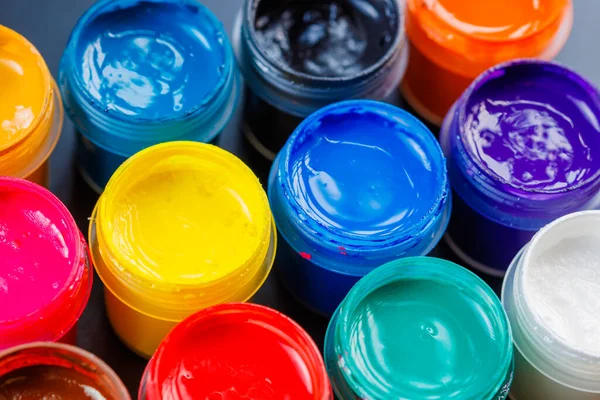 full-frame close-up background of opened small gouache paint jars