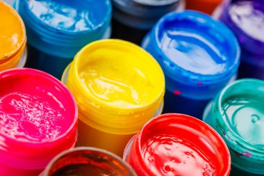 full-frame close-up background of opened small gouache paint jars