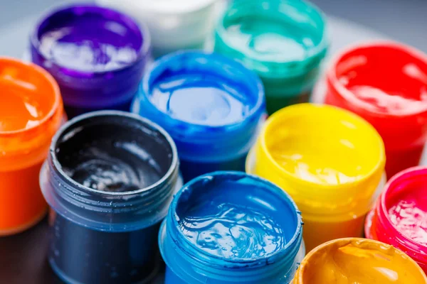full-frame close-up background of opened small gouache paint jars