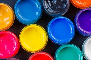 full-frame close-up background of opened small gouache paint jars