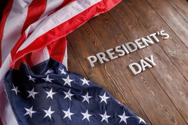 words presitdents day laid with silver letters on wooden surface near US flag