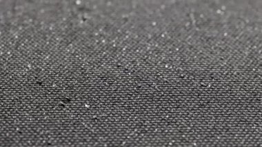 spinning background of black hydrophobic fabric while covering with water drops