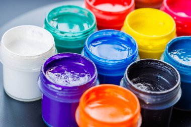 full-frame close-up background of opened small gouache paint jars