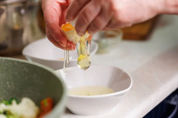 Tangan senior wanita kaukasia memecahkan telur ayam putih di atas mangkuk putih — Stok Foto