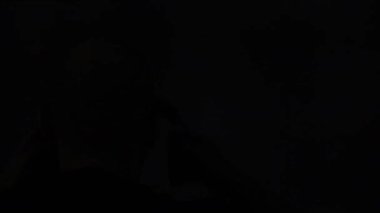 bald man silhouette putting on headphones in front of blinking screen