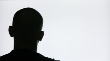 bald man in glasses with beard moving his head in front of blinking screen