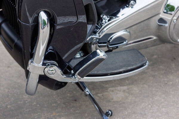 close view on chrome classic road motorcycle on asphalt parking at spring day - close side view on folded footboard