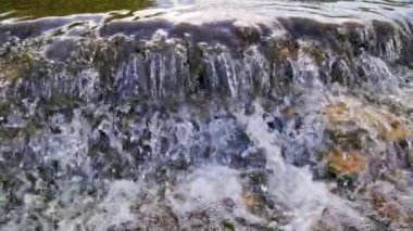 the flowing water small rapid waterfall on river in slow motion at daylight - full-frame background