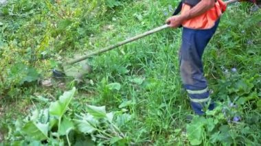 Man mows the grass with a manual petrol lawn mower in Slow Motion. Process of lawn trimming with a hand mower. Side view on utility worker mows the green grass. Gardening care tools. Summer day.
