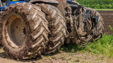 dirty double wheels of big agriculture tractor on dirt road at summer day diredt sun light