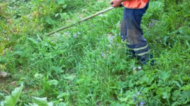 Man mows the grass with a manual petrol lawn mower in Slow Motion. Process of lawn trimming with a hand mower. Side view on utility worker mows the green grass. Gardening care tools. Summer day.