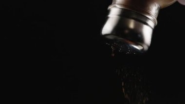 red pepper falling out from pepper-pot on black background in slow motion