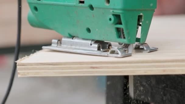 ソーダストは ジグソーが板合板に切断する際に金属製のブレードから飛び降ります 大工は合板板の端を切り取る ジグソーは合板の一部にカットします サイドビュー — ストック動画
