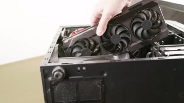 caucasian hand trying to fit a new big black triple fan graphics card into black pc case, card does not fit because it is too big