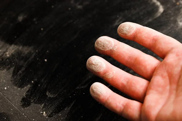 caucasian hand with dust on finger tips after touching black dusty surface, closeup with selective focus