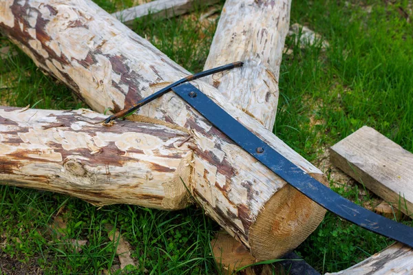 forged steel stripe connection of wooden log beams for roof support girder framework laid on green grass at summer day during assembly